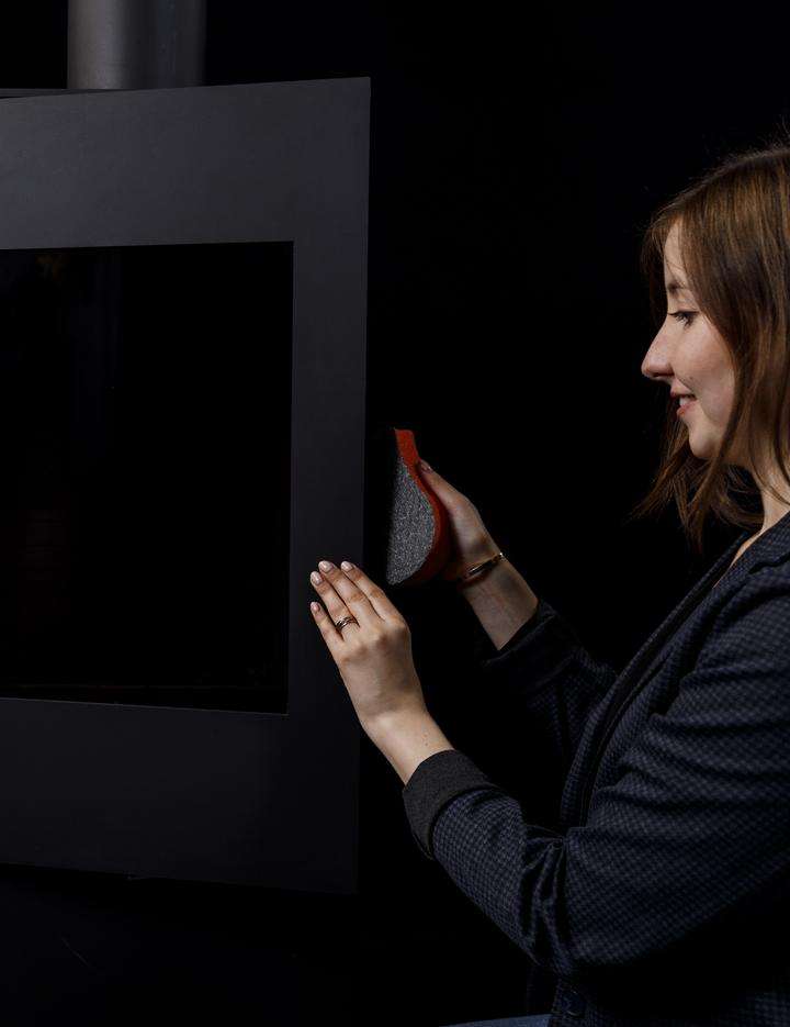 Woman standing beside a fireplace with a ROBAX NightFlame coated fire-viewing panel