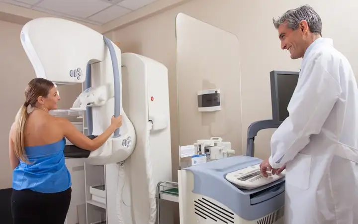 Male doctor talking to a female patient being examined by medical equipment in a hospital