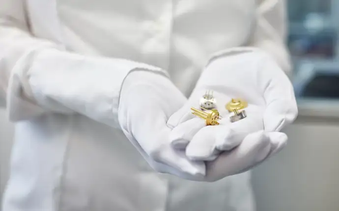 Person in lab clothing holding electronic components produced using glass-to-metal sealing in his hands.	