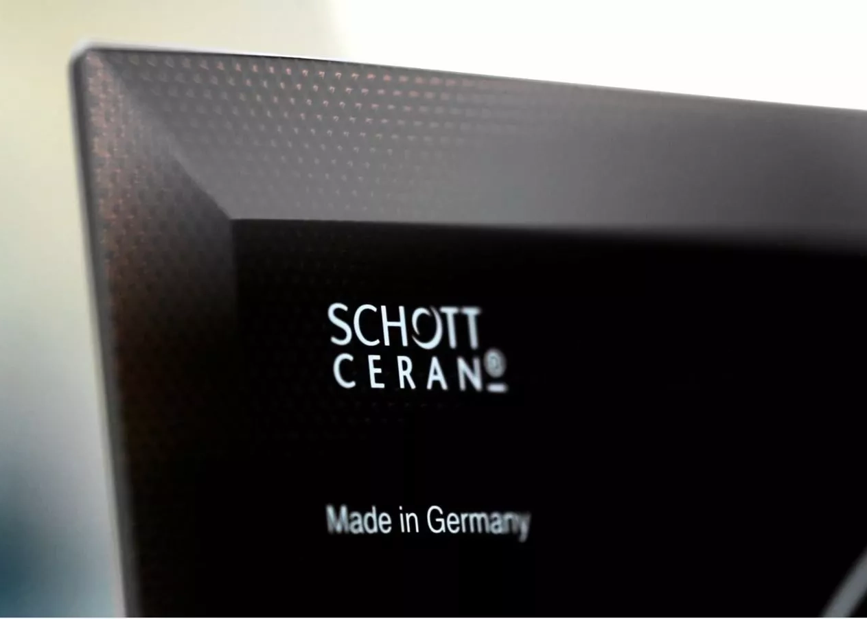  Corner of a black SCHOTT CERAN® glass-ceramic cooktop panel with logo