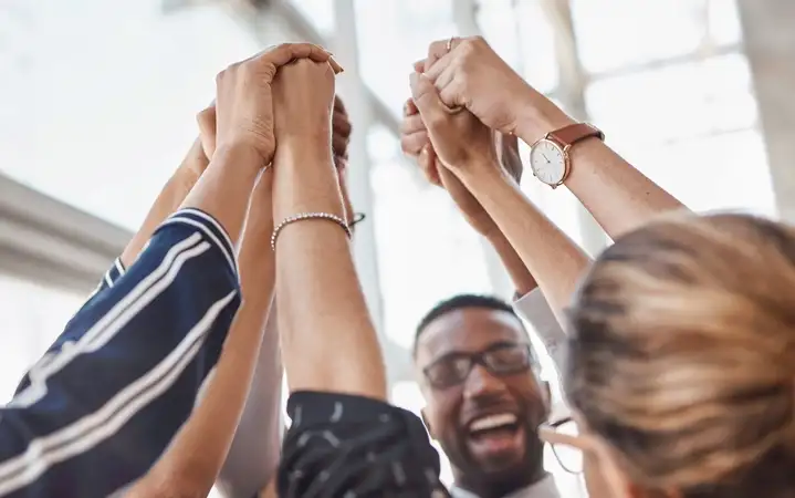 Team of people holding each others hands in the air