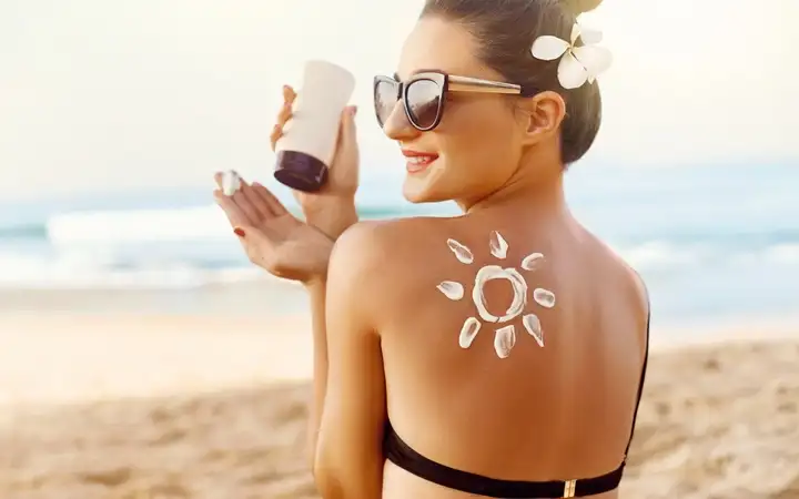 Woman at the beach applying tanning lotion