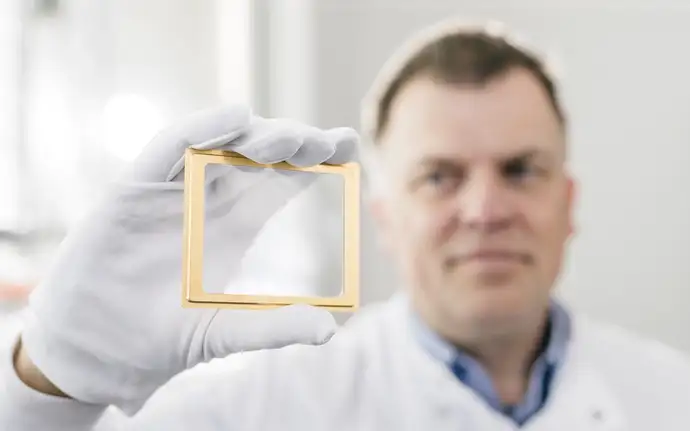 Hands wearing white gloves each hold a MEMS component.