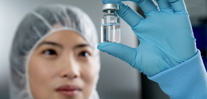 Women looking at filled vial in one hand.