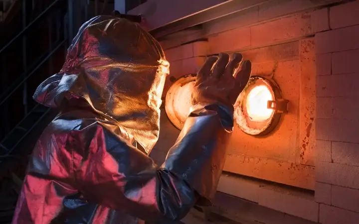 Man looking into glass melting tank