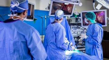 Doctors watch HD monitors while performing minimally invasive robotic surgery