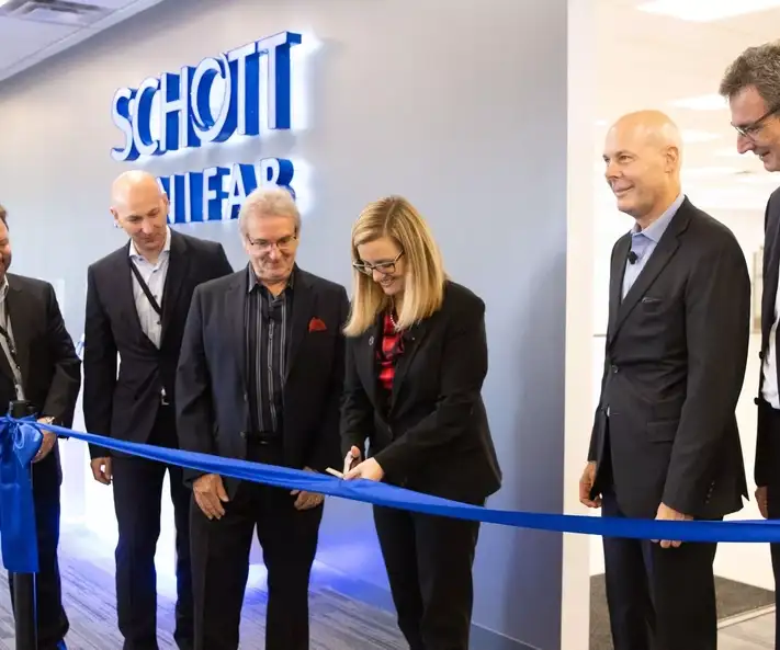 A lady cuts a blue ribbon with a pair of scissors.