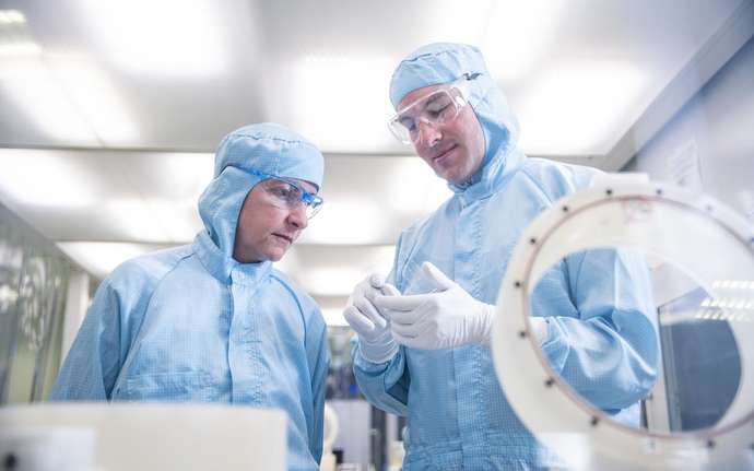 two employees in cleanroom production holding a NEXTERION(R) glass substrate in the hand