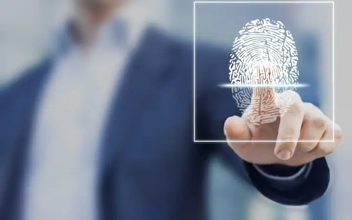 Man in a business suit placing finger on fingerprint sensor