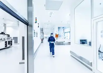 A woman in a protection suit walks through a lab.