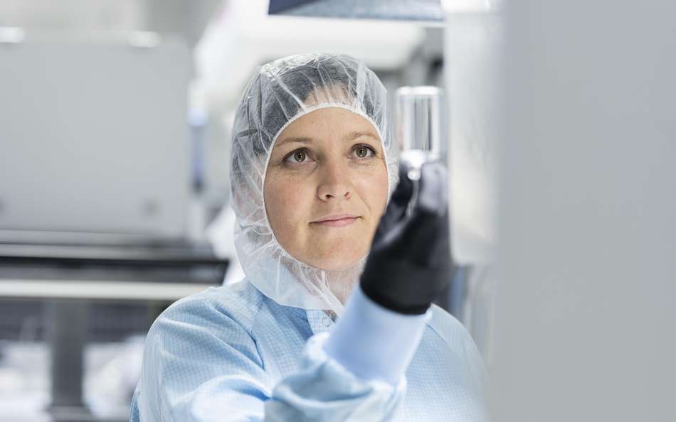 Female scientist inspecting a glass vial in a laboratory
