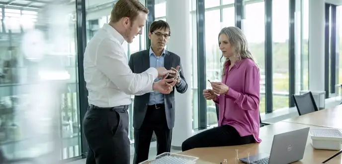 Mulheres e homens em pé discutindo a embalagem primária