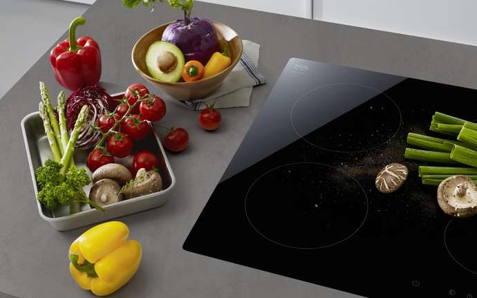 Selection of vegetables next to a black SCHOTT CERAN Miradur® glass-ceramic cooktop