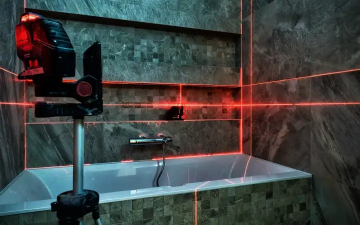 Red laser metrology equipment measuring a bathroom