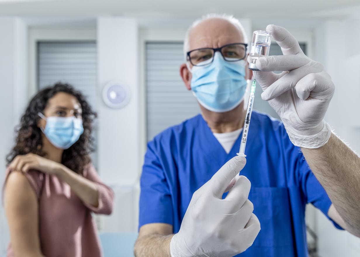 Doctor prepares a syringe to vaccinate a patient 