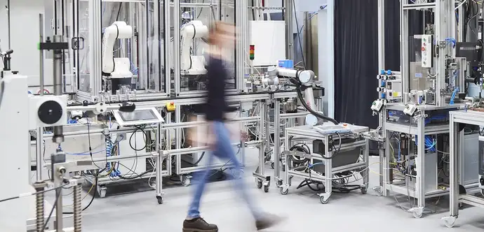 Mujer joven caminando por un laboratorio en el Instituto Tecnológico de Karlsruhe (KIT)