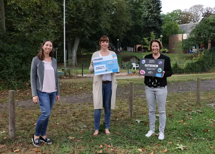 Drei Frauen überreichen Spendenscheck