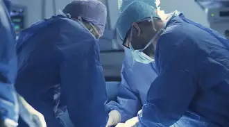 A group of gowned surgeons performing a procedure.