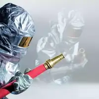 Fire fighter in silver protective suit holding a red water hose