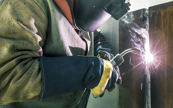 Worker operating welding equipment creating sparks