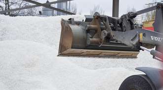 An excavator takes the bottles onto the shovel in the cullet store	