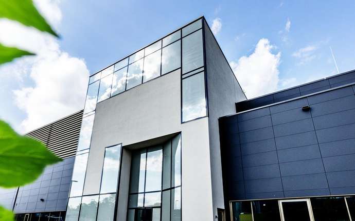 View of a glass building with green leaves in the foreground.