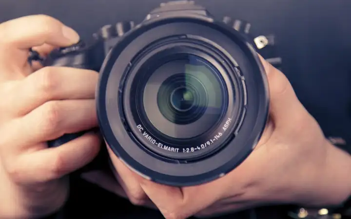 Hands holding a large digital camera 