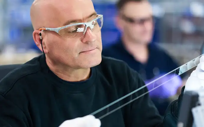 Technician inspecting glass substrate in laboratory setting