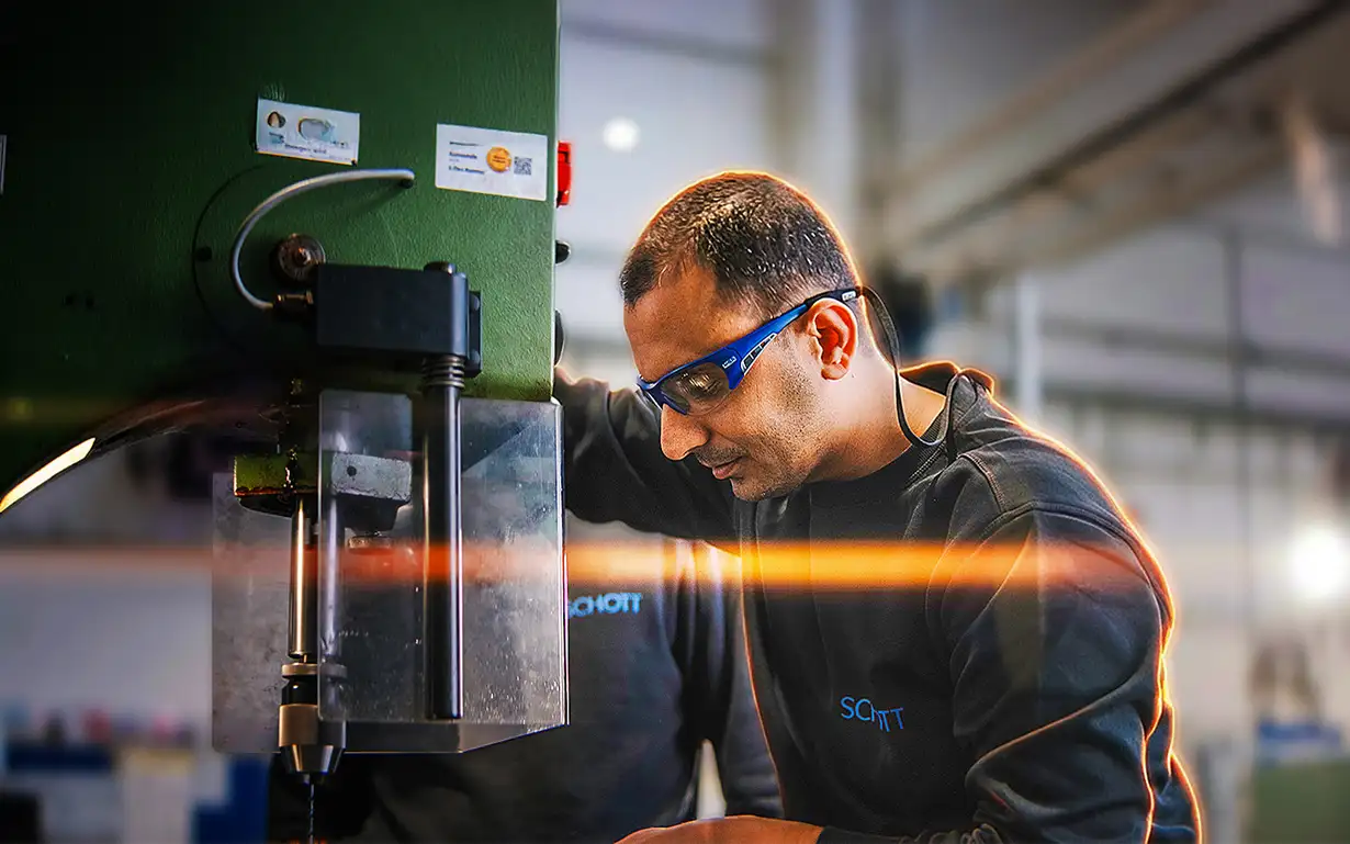 Person arbeitet an einer großen grünen Industriemaschine in einer Werkhalle.
