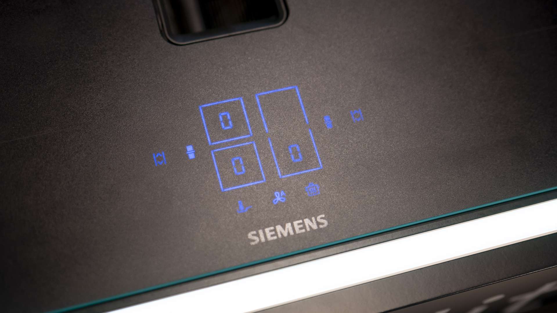 Siemens induction hob with blue touch controls, integrated downdraft and high-quality matt black glass-ceramic surface.