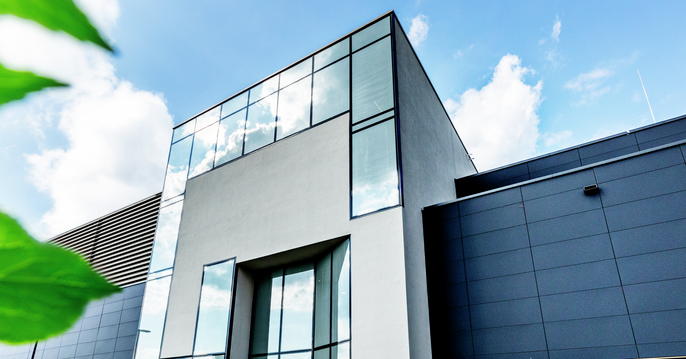 View of a glass building with green leaves in the foreground.