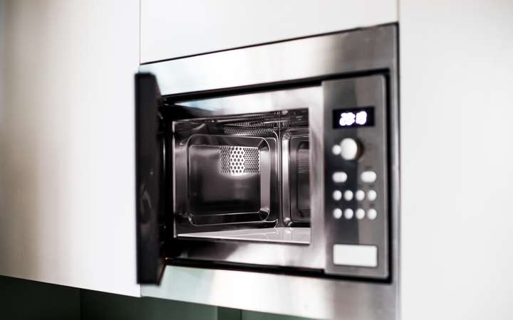 Open microwave oven with visible interior and control panel