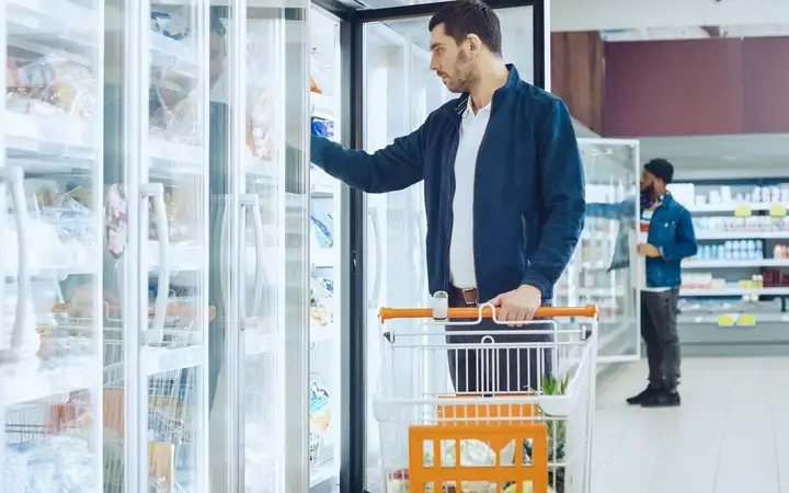 Refrigerador de supermercado com frente de vidro transparente repleto de alimentos