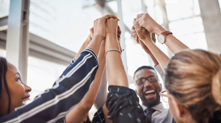 Team of people holding each others hands in the air