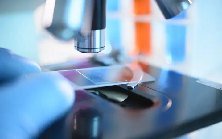 Scientist placing a glass slide under a microscope