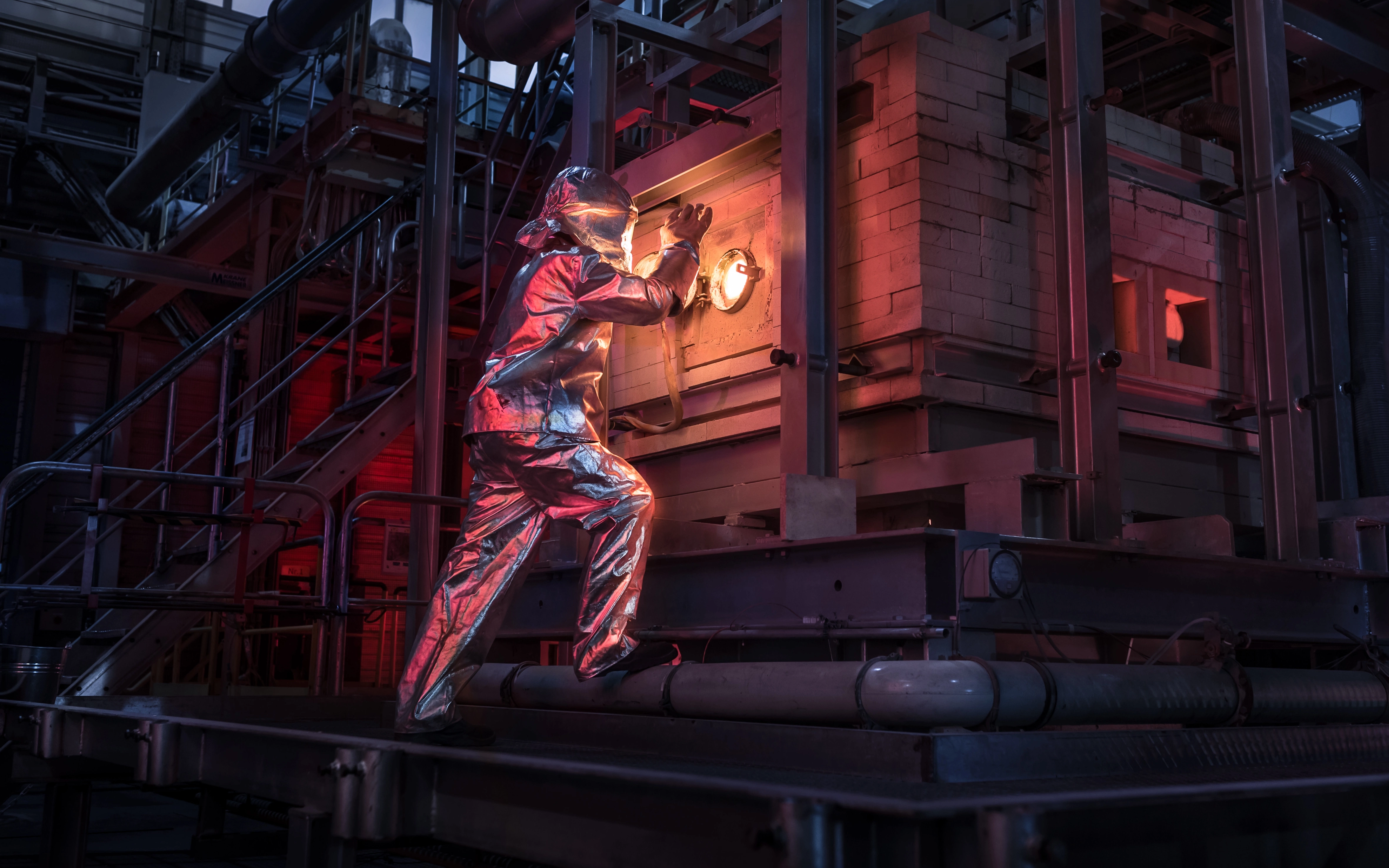 SCHOTT engineer in safety suit looking inside a glass melting tank