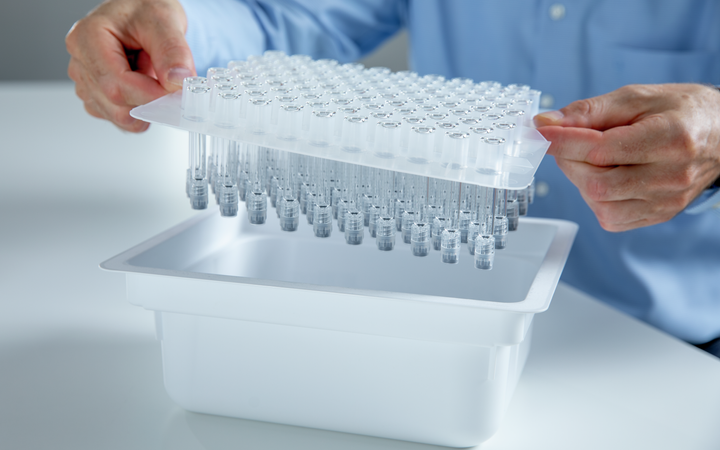 Man holding a nest of syringes standing at a table.