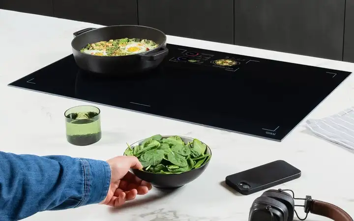 SCHOTT CERAN® Luminoir™ TFT cooktop in a modern kitchen with a dish, recipe display, and ingredients. 