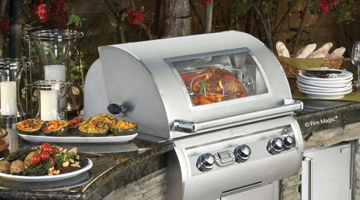Silver outdoor grill with glass-ceramic viewing panel surrounded by food
