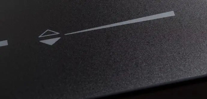 Close-up view of a textured black surface with white graphical elements, including a triangle and a pointed line.