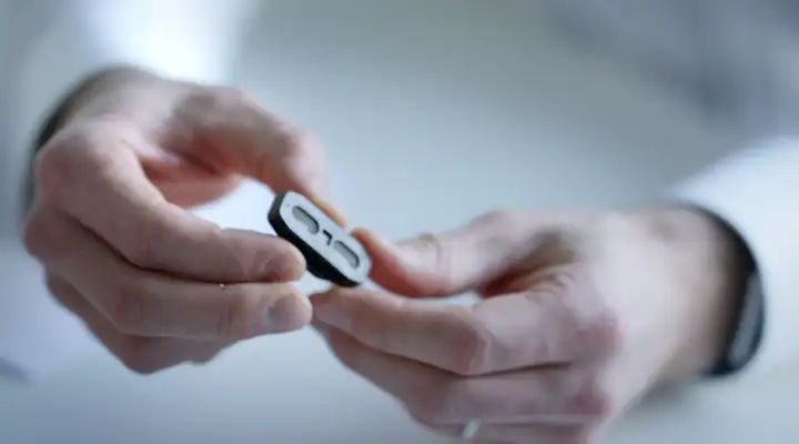 Close-up of hands holding a MosaiQ diagnostic platform.