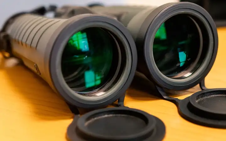 Pair of binoculars with green reflections in lenses