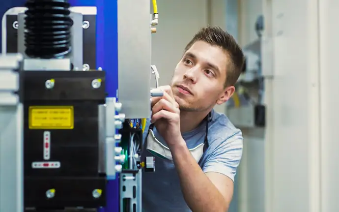 Junger Mann arbeitet an der Elektronik einer Maschine