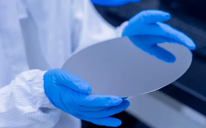 Technician holding a precision glass wafer used as substrate for wafer-level optics