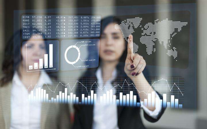 Two business women in an office analyzing data on a touchscreen