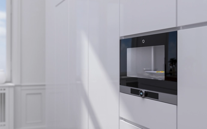 Weiße Küchenfront mit einer schwarzen Mikrowelle mit dem neuen SCHOTT® micro clear fabric Glas.
