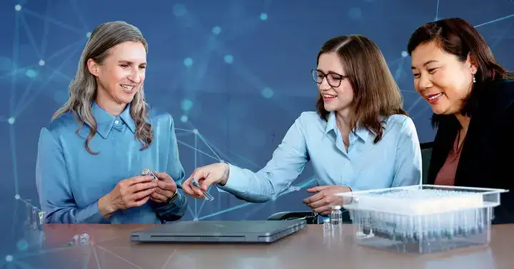 Women holding samples while sitting at a table with syringes