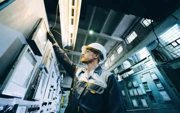 Man in workwear looking at a display on industrial equipment