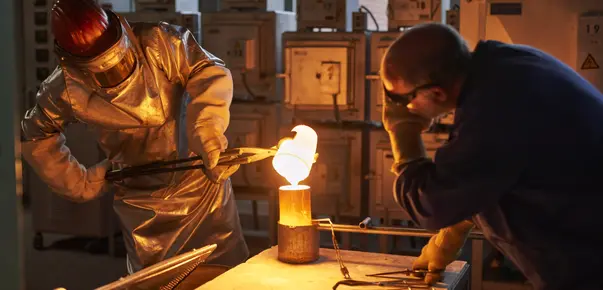  A scientist in full-body protection pours red, molten-hot glass as part SCHOTT's research into melting glass with electricity
