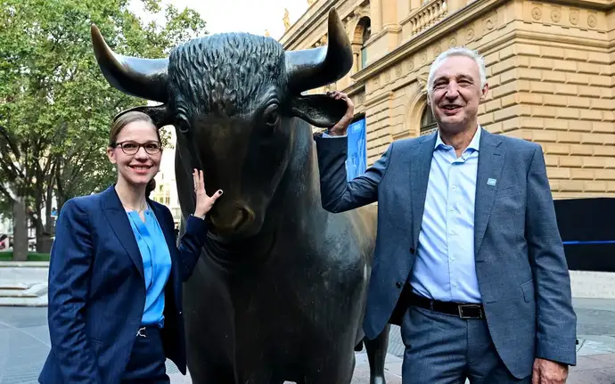 	A woman and a man stand next to the bull of the Frankfurt Stock Exchange.